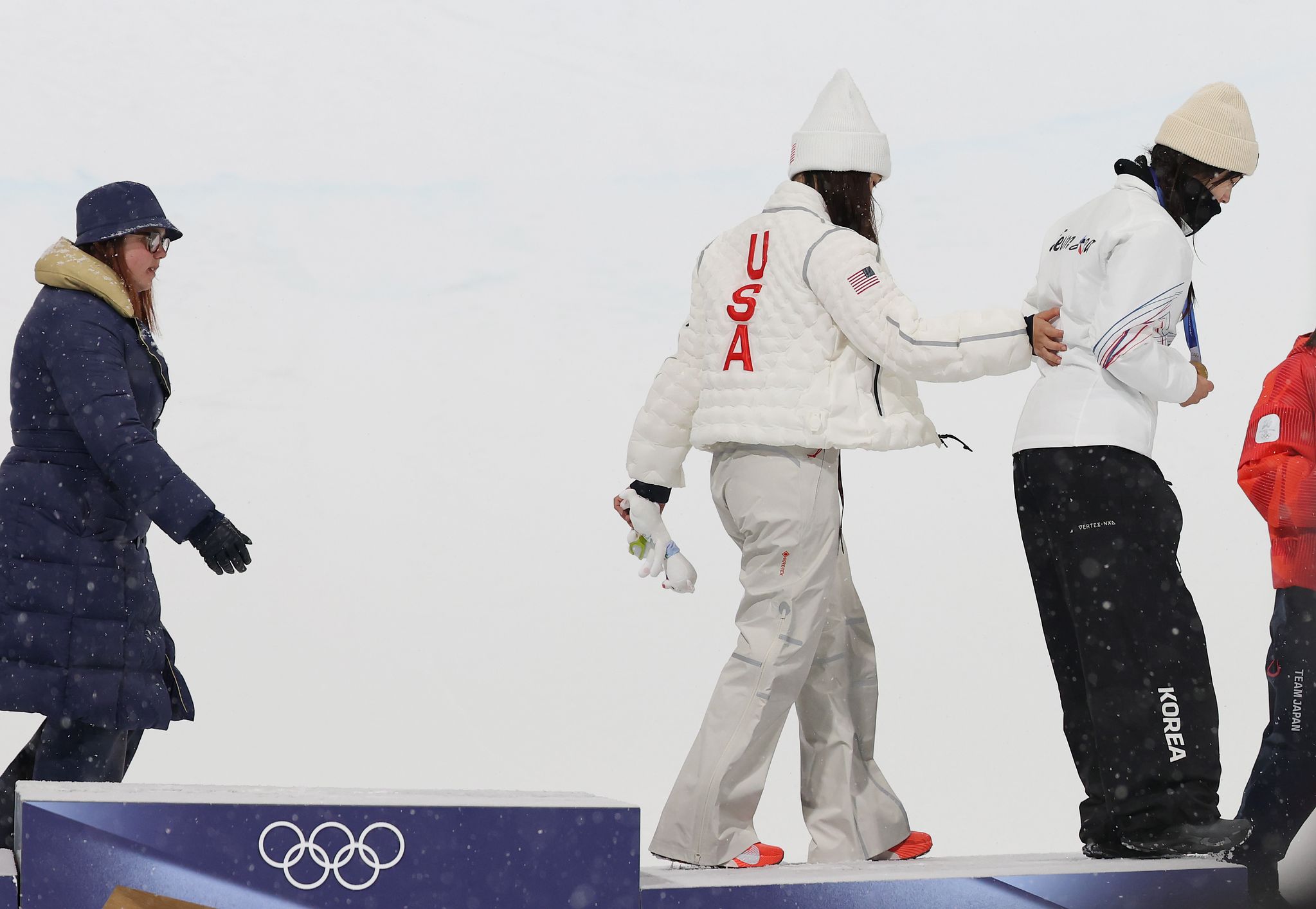 12일(현지시간) 이탈리아 리비뇨 스노파크에서 열린 2026 밀라노-코르티나담페초 동계올림픽 스노보드 여자 하프파이프 결승에서 금메달을 따낸 최가온이 메달 세리머니를 마치고 클로이 김의 부축을 받으며 시상대를 내려가고 있다.