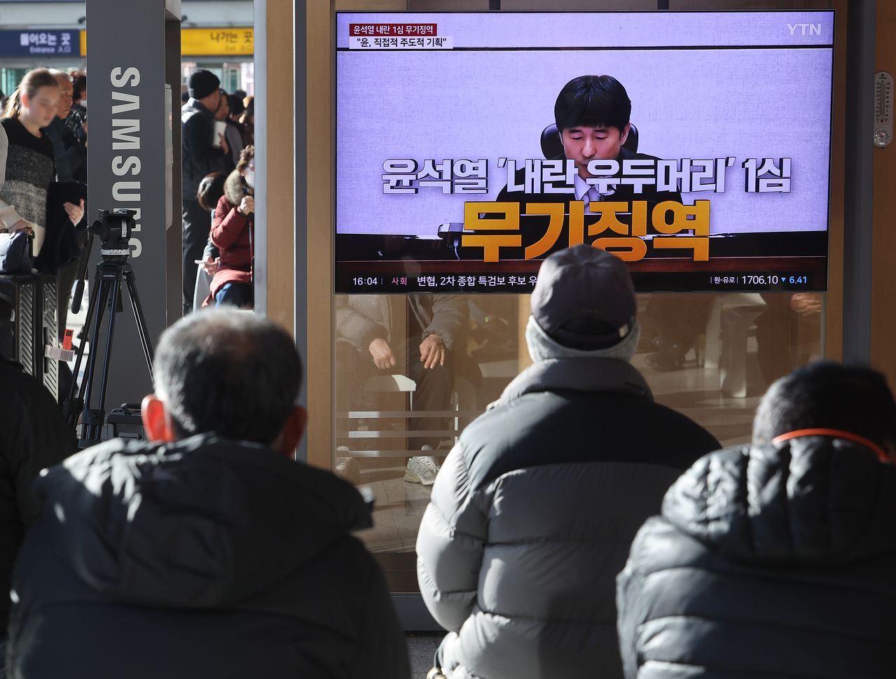 19일 서울역 대합실에서 시민들이 12·3 비상계엄 관련 내란 우두머리 혐의로 기소된 윤석열 전 대통령에 대한 1심 선고공판 TV 생중계를 시청하고 있다.   연합뉴스