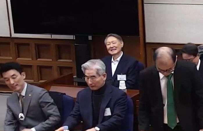 19일 서울중앙지방법원에서 열린 내란 우두머리 혐의 사건 1심 선고 공판에 출석한 윤석열 전 대통령이 변호인과 대화하며 미소짓고 있다. 아래는 김용현 전 국방부 장관. 재판부는 윤 전 대통령에게 무기징역을 선고했다. 연합뉴스 