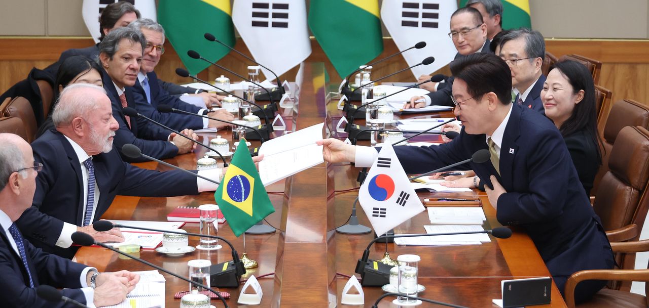 이재명 대통령이 23일 청와대에서 열린 한-브라질 확대정상회담에서 룰라 브라질 대통령 요청으로 책에 사인한 뒤 전달하고 있다. 연합뉴스