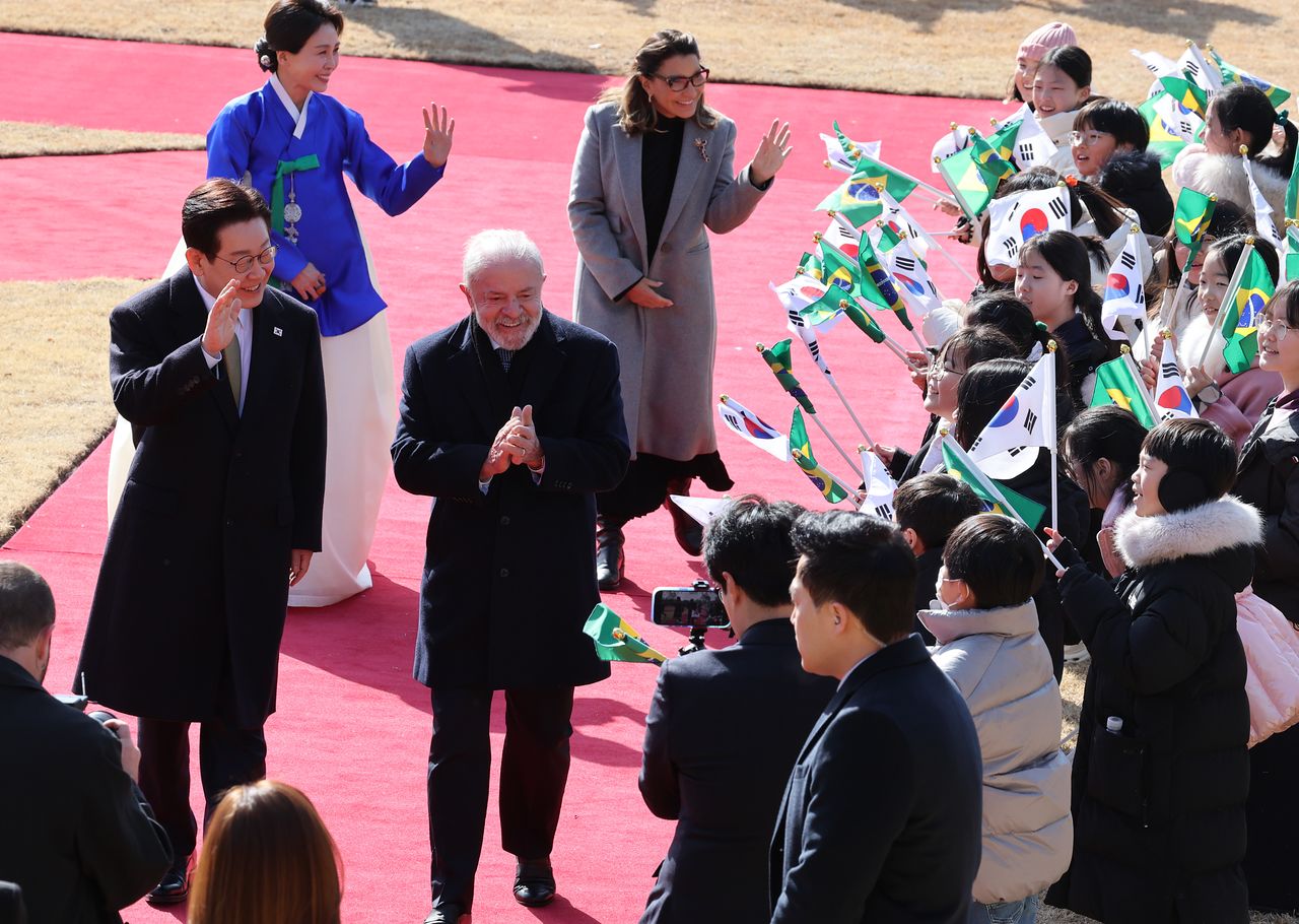 이재명 대통령과 루이스 이나시우 룰라 다 시우바 브라질 대통령, 김혜경 여사와 잔자 룰라 다 시우바 여사가 23일 청와대 대정원에서 열린 공식환영식에서 깃발을 흔드는 화동들에게 인사를 하고 있다. 청와대사진기자단 