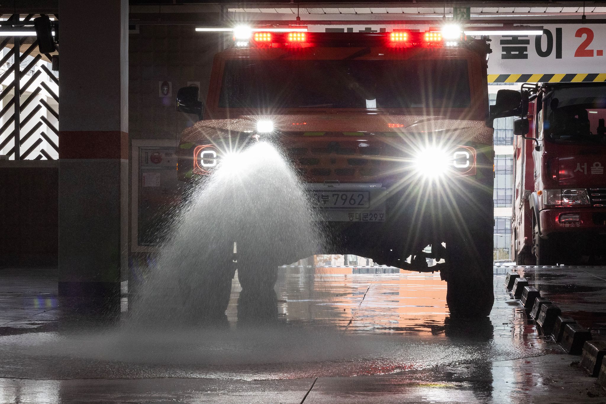 저상소방차가 지하주차장으로 들어서서 물을 뿌리며 이동하고 있다.