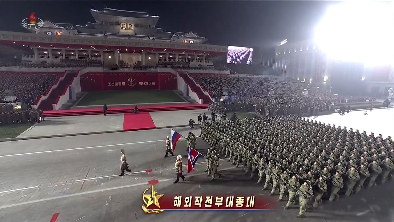 북한이 지난 26일 조선중앙TV를 통해 중계된 당9차대회 기념열병식에서 우크라이나 전쟁에 파병됐던 해외작전부대와 해외공병연대 소속 군인들이 러시아 국기와 인공기를 앞세워 들고 행진하고 있다. 조선중앙TV 캡처, 연합뉴스