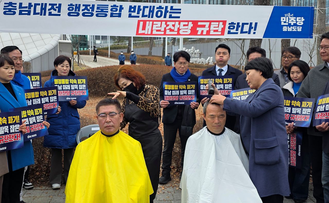 27일 오전 충남도청 앞에서 열린 더불어민주당 충남도당 주최 '행정통합 가로막는 매향 5적 규탄대회'에서 참석자들이 삭발하고 있다. 왼쪽부터 오인철 충남도의회 부의장, 류제국 천안시의회 부의장. 연합뉴스