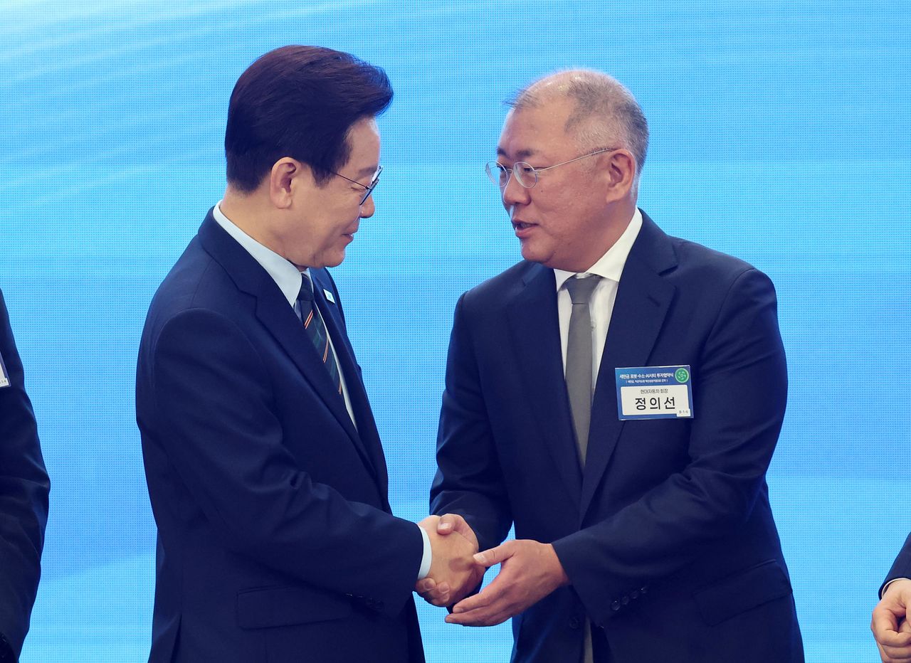 이재명 대통령이 27일 전북 군산새만금컨벤션센터에서 열린 새만금 로봇,수소,AI 시티 투자협약식에서 기념촬영을 마친 뒤 정의선 현대차그룹 회장과 악수하고 있다.연합뉴스
