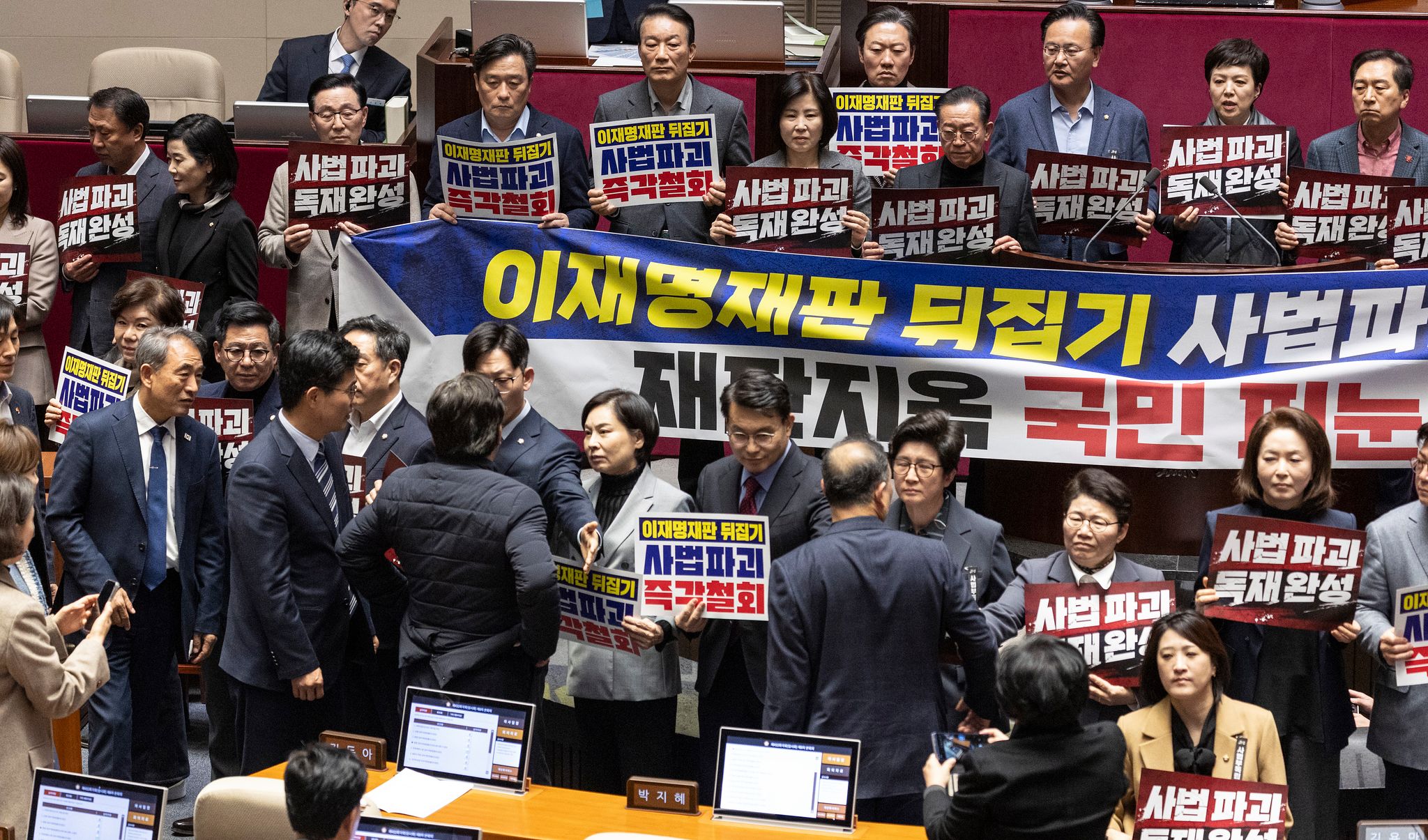 27일 국회에서 열린 2월 임시국회 8차 본회의에서 전날 상정된 헌법재판소법 일부개정법률안(재판소원제)에 대한 무제한 토론(필리버스터) 종결을 위한 투표가 시작되자 국민의힘 의원들이 손팻말과 피켓을 들고 시위를 펼치는 동안 민주당 양문석 의원과 국민의힘 서명옥 의원이 설전을 벌이고 있다.   두 의원의 설전은 국민의힘 시위를 휴대폰으로 찍던 조국혁신당 이해민 의원을 국민의힘 서명옥 의원이 손팻말로 제지하면서 시작됐다.   이를 뒤에서 지켜보던 민주당 양문석 의원이 서 의원에게 강하게 항의하면서 여야 의원들의 말싸움이 시작됐다. 연합뉴스