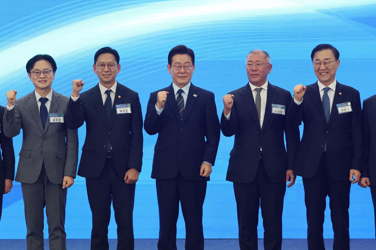 이재명 대통령과 000 등이 27일 전북 군산시 새만금 컨벤션센터에서 열린 새만금 로봇·수소·AI 시티 투자협약식에서 투자협약을 체결한 뒤 기념촬영을 하고 있다. 왼쪽부터 김정관 산업통상부 장관, 배경훈 부총리 겸 과학기술정보통신부 장관, 이재명 대통령, 정의선 현대자동차 회장, 김윤덕 국토교통부 장관. 뉴스1