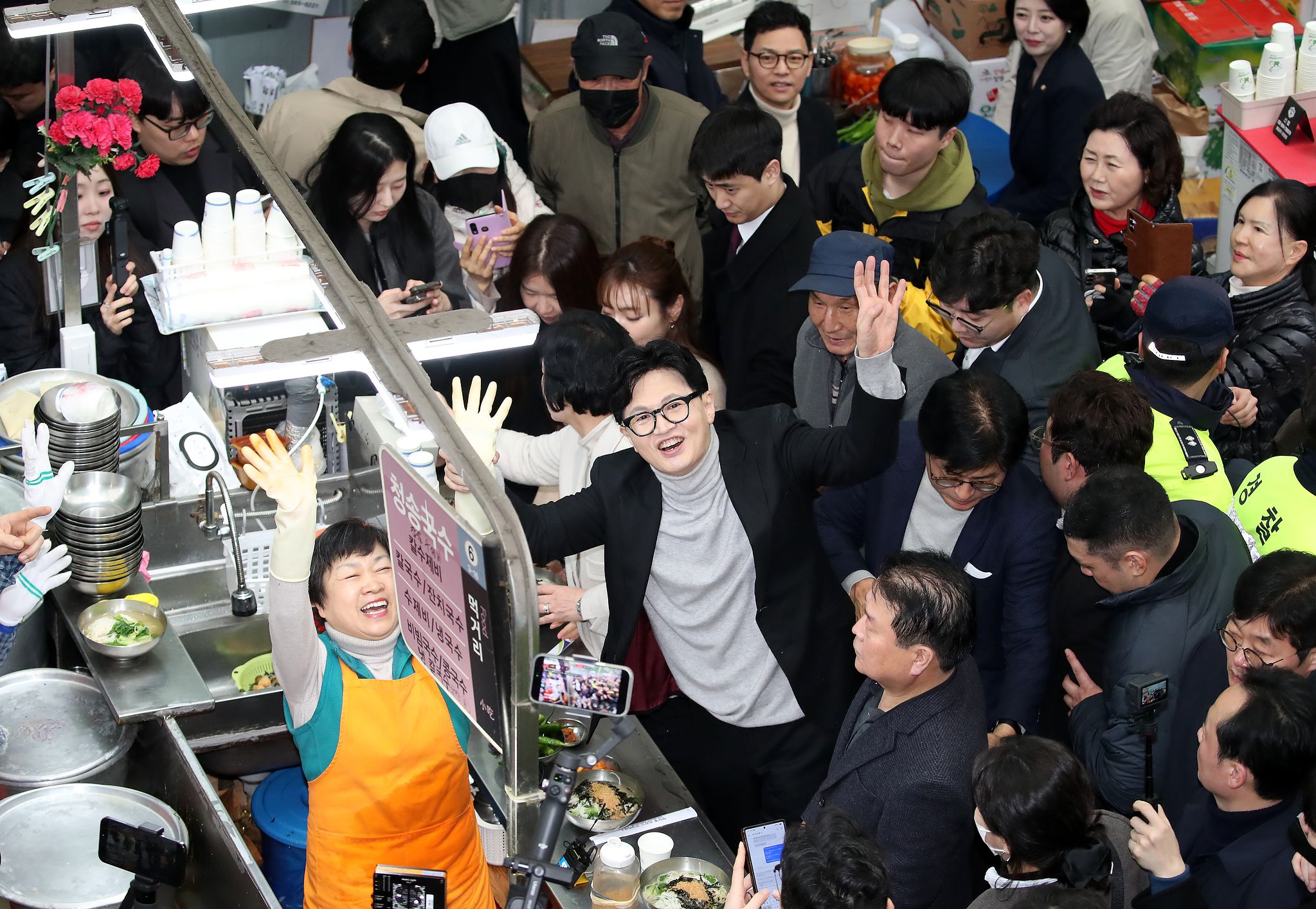 한동훈 전 국민의힘 대표가 27일 오후 대구 중구 서문시장 국수골목을 찾아 상인과 함께 손을 흔들고 있다.뉴스1