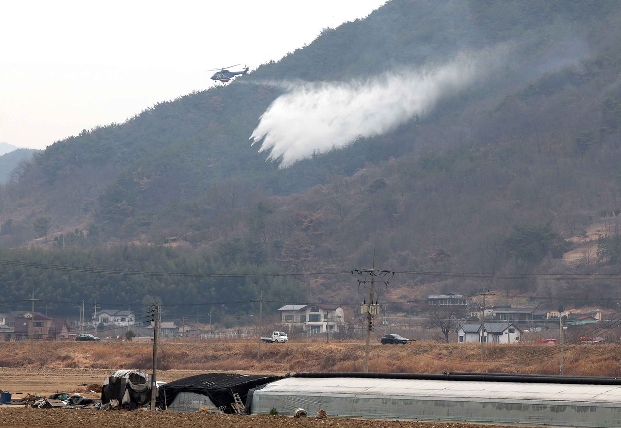 산불 진화 헬기가 지난달 24일 오전 경남 밀양시 삼랑진읍 민가 주변에서 산불 진화 작업을 하고 있다. 연합뉴스