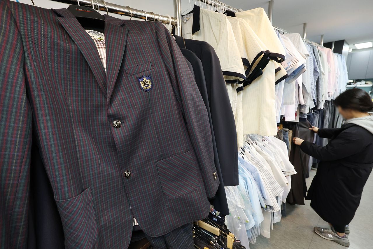 교육부가 정장 교복 폐지 권고를 발표한 지난달 26일 학부모가 서울의 한 나눔매장에서 교복을 살펴보고 있다. [연합뉴스]