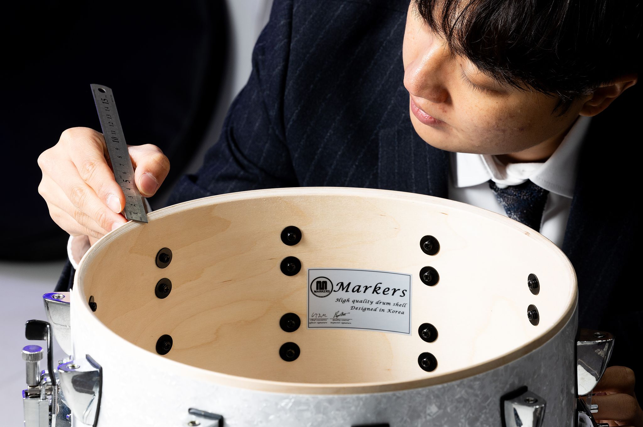 박 대표가 마커스뮤직의 기술력의 정수인 플라이 방식으로 제작된 드럼쉘(원형통)을 살펴보고 있다. 6~8겹의 얇게 핀 나무를 압축하여 제작하는 방식으로 나무 하나를 동그랗게 다 파내어 제작하는 솔리드 방식에 비해 단가를 줄일 수 있다.  