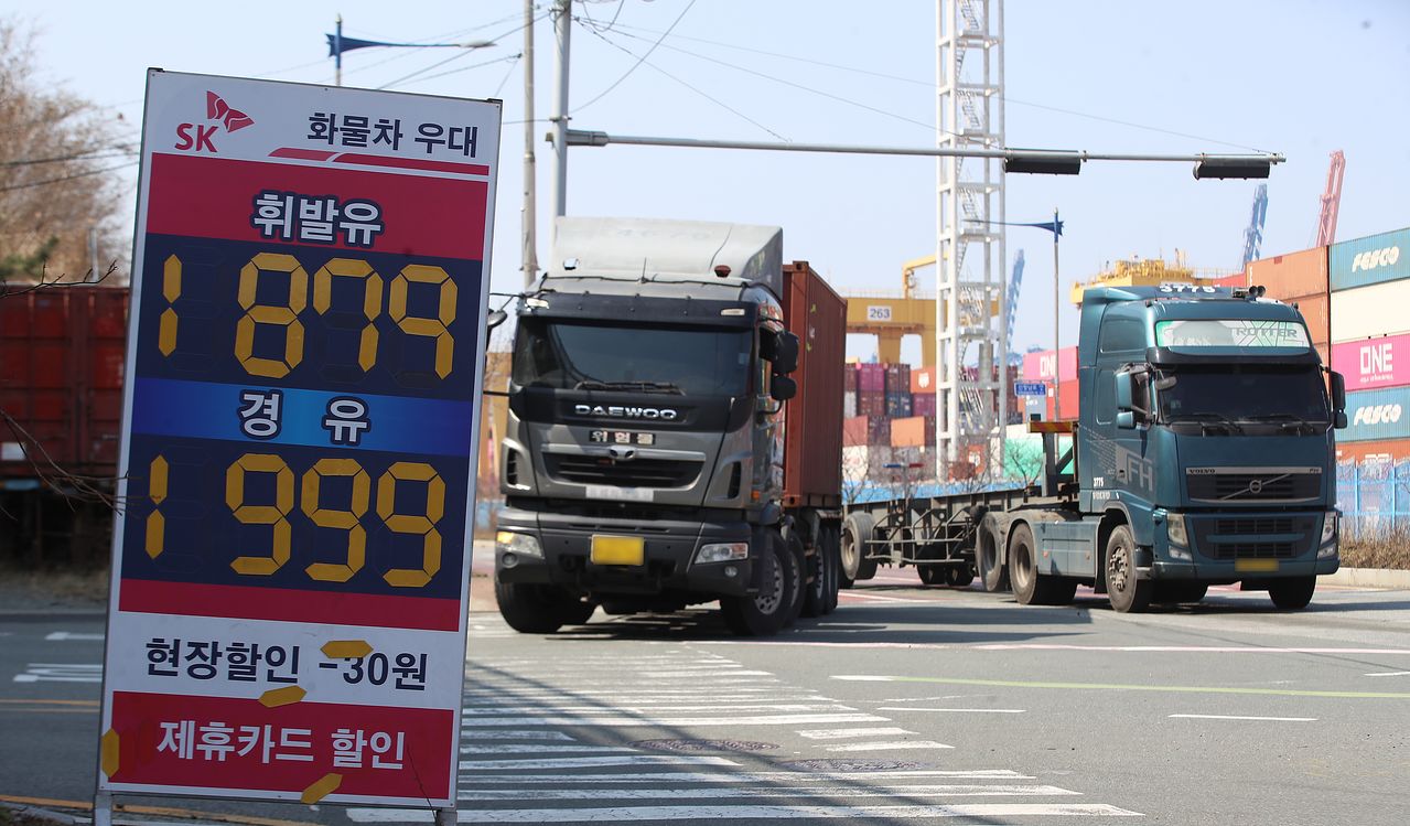지난 10일 경유 가격이 1999원으로 적혀 있는 부산 강서구 부산신항 인근 한 주유소 유가 안내판 뒤로 화물차들이 지나가고 있다. 뉴스1