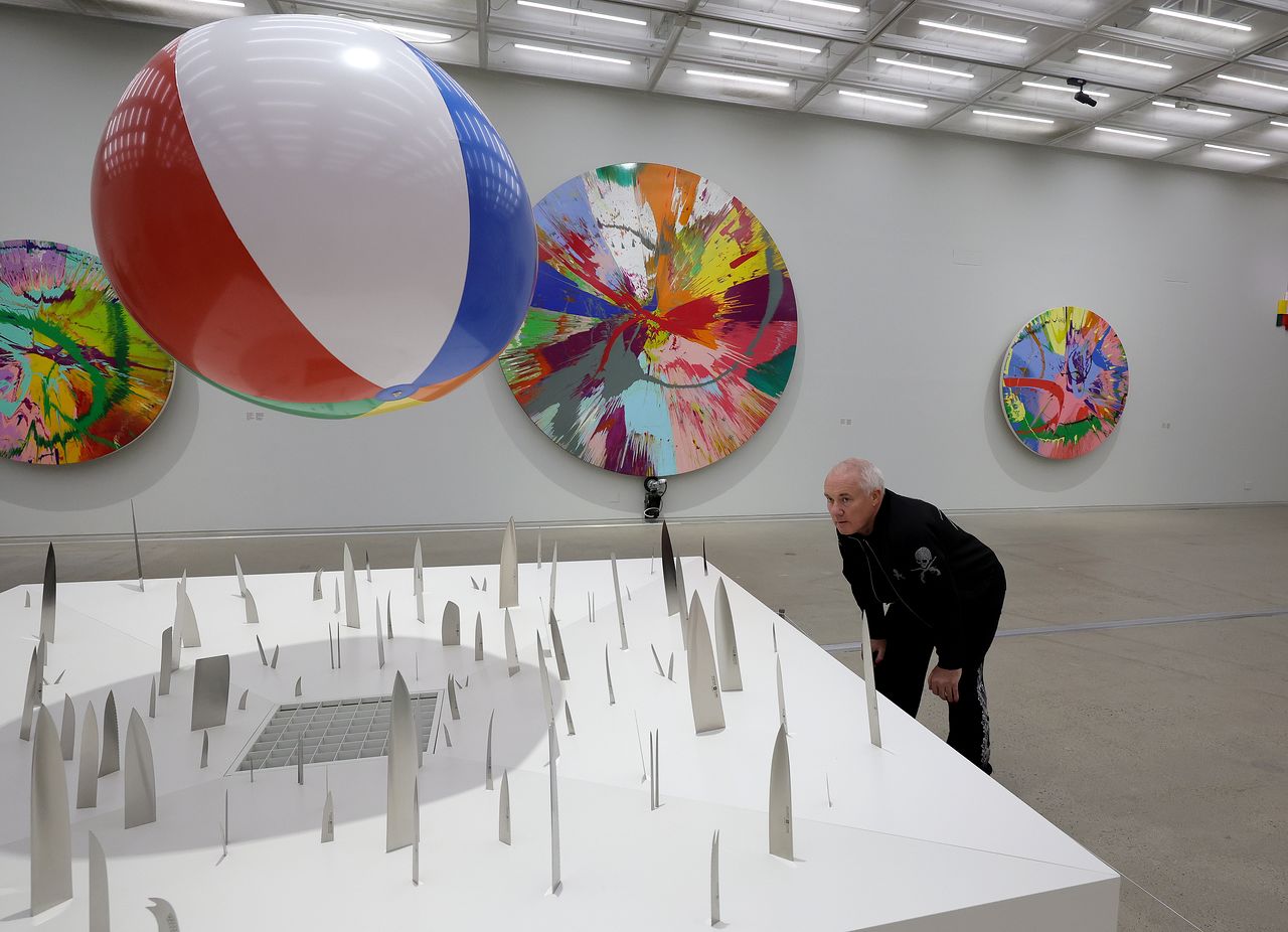 대규모 회고전을 앞둔 데이미언 허스트가 칼 위에 비치볼을 띄운 '사랑의 취약성'(2000)을 보고 있다. 뒤의 둥근 그림은 회전판 위에 물감을 흘린 '스핀 페인팅' 연작. 장진영 기자