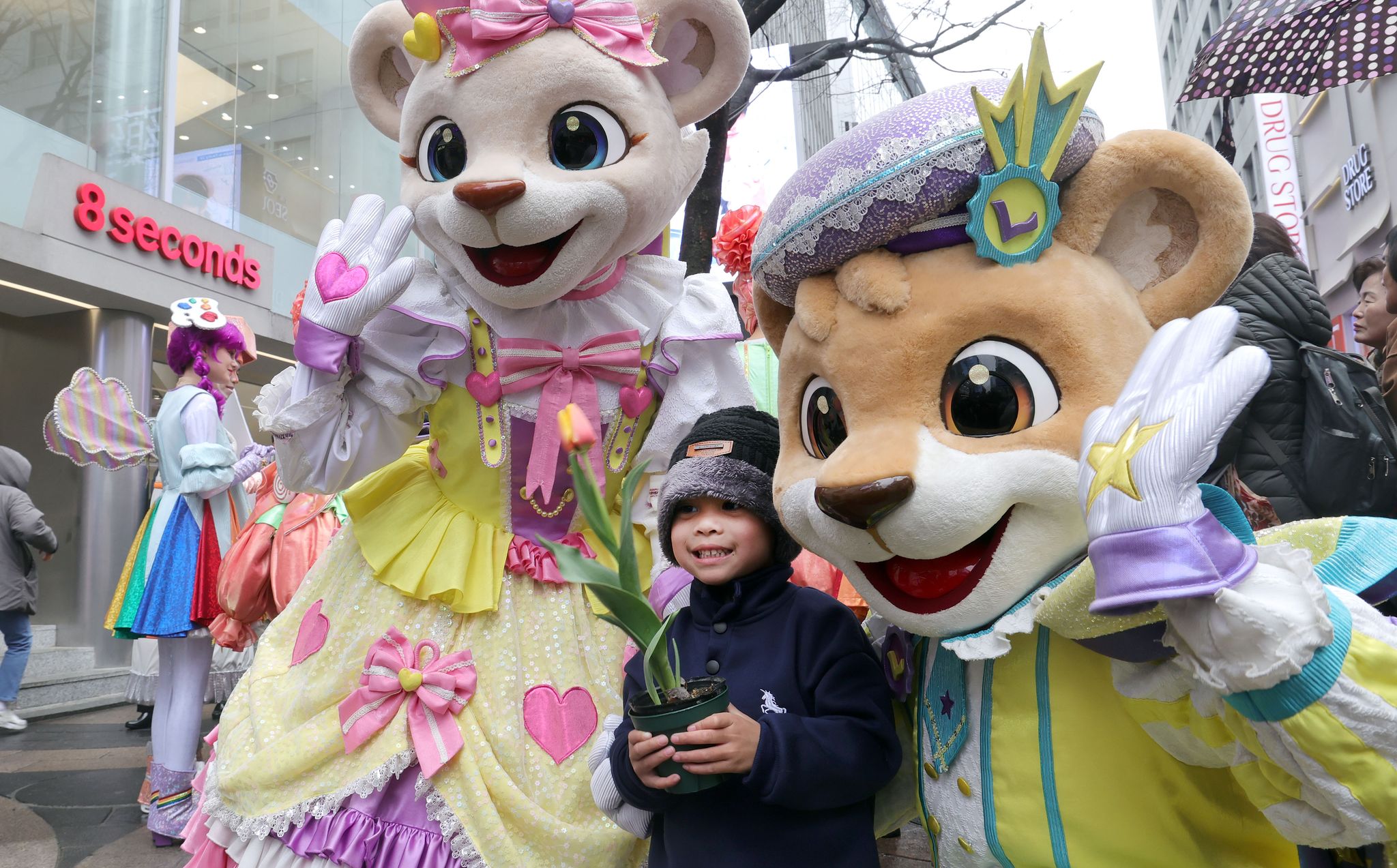 튤립축제 개막을 이틀 앞둔 18일 오후 서울 명동에서 외국인 어린이가 에버랜드 캐릭터와 사진을 찍고 있다.