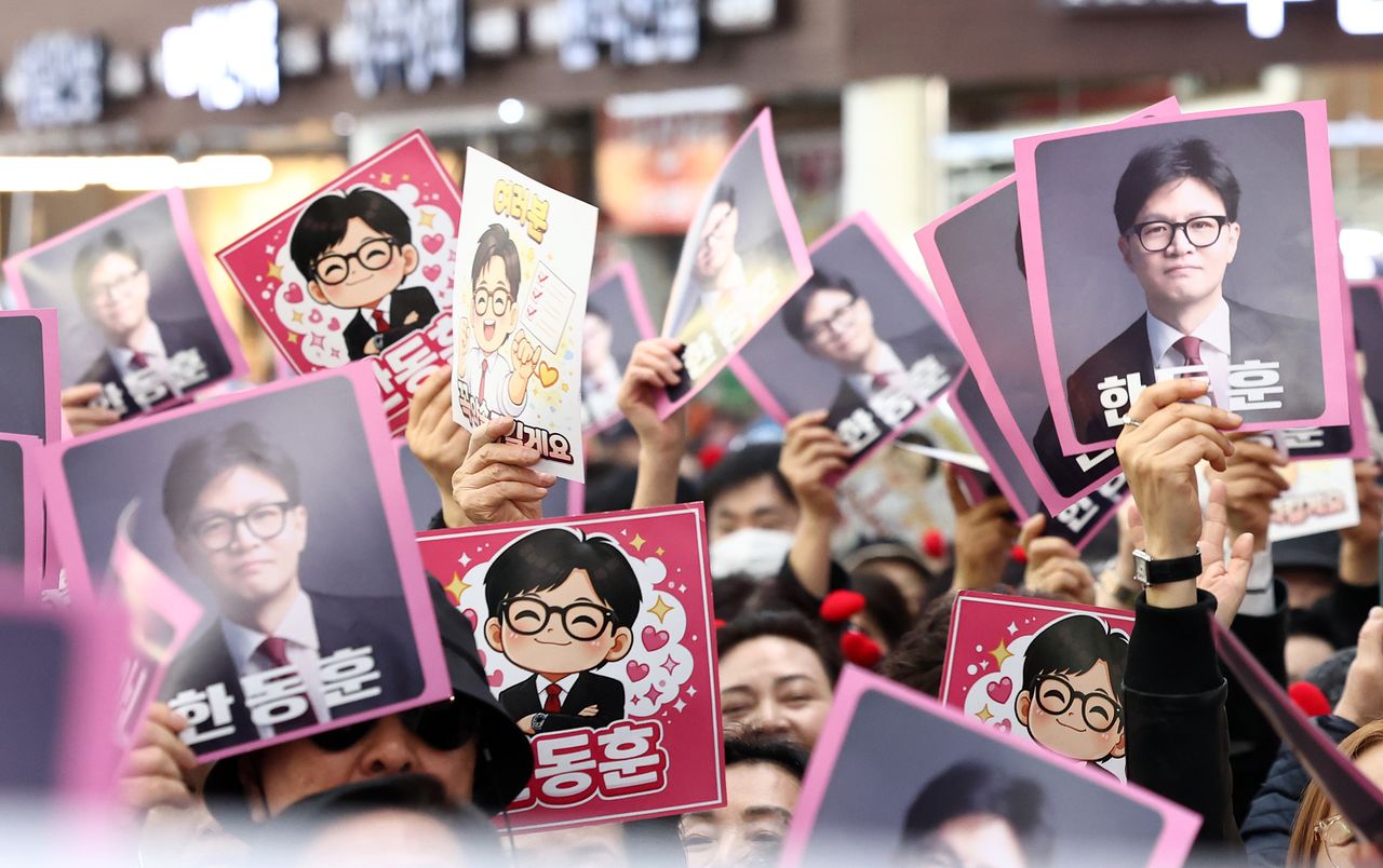 22일 오후 서울 동대문구 경동시장에서 한동훈 전 국민의힘 대표의 방문을 앞두고 지지자들이 피켓을 흔들고 있다. 뉴스1