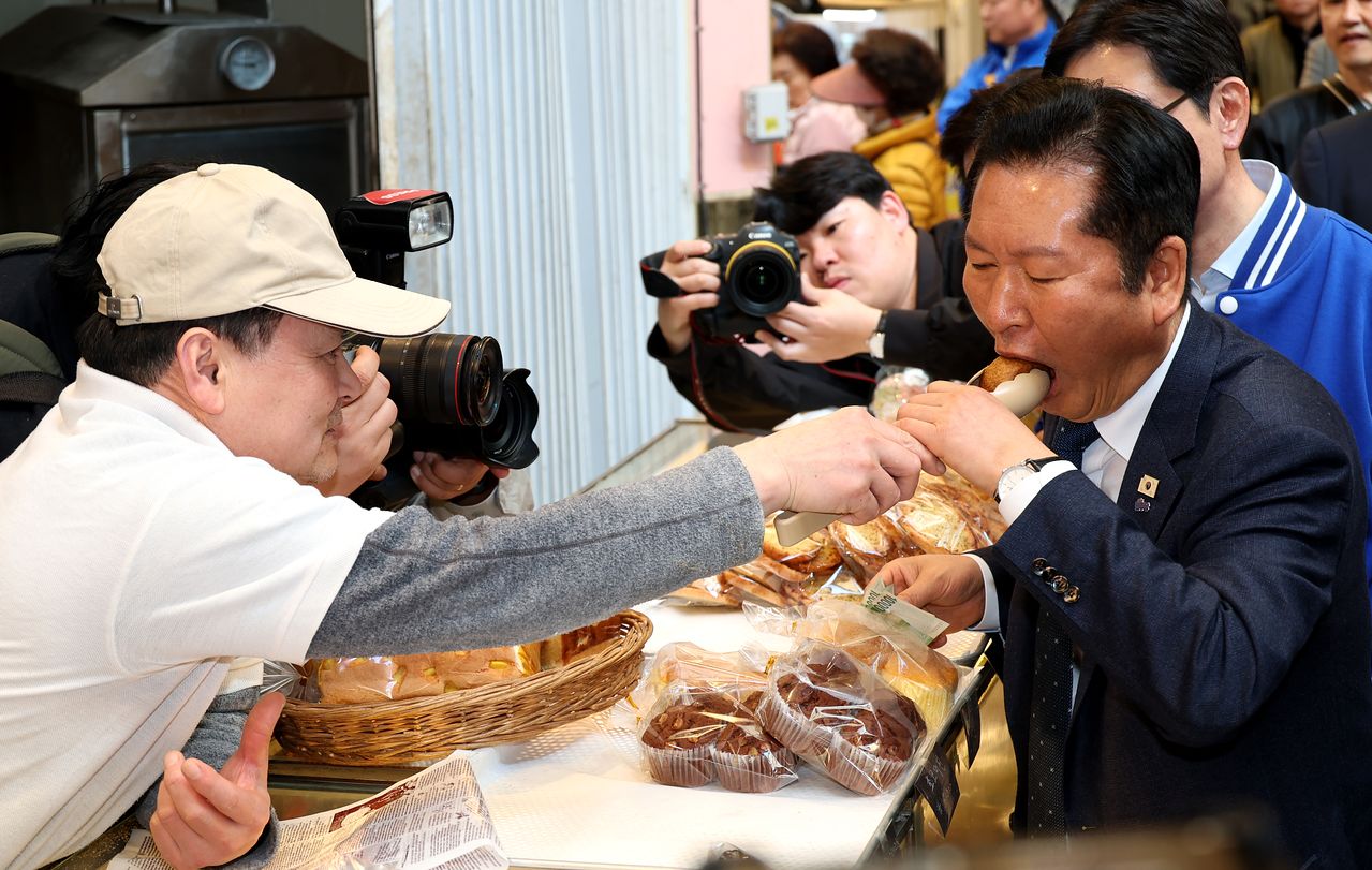 정청래 더불어민주당 대표가 23일 오후 경남 양산시 중부동 양산남부시장에서 찹쌀도넛을 먹고 있다. 연합뉴스