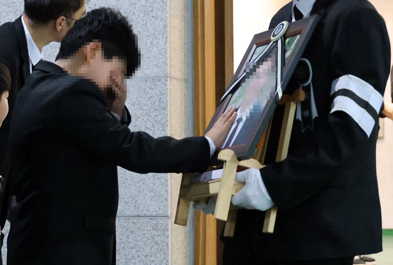 25일 대전 대덕구 안전공업 화재 참사 희생자의 발인식이 엄수된 가운데, 참사로 아버지를 잃은 초등학생 아들이 고인의 얼굴을 쓰다듬고 있다. 연합뉴스