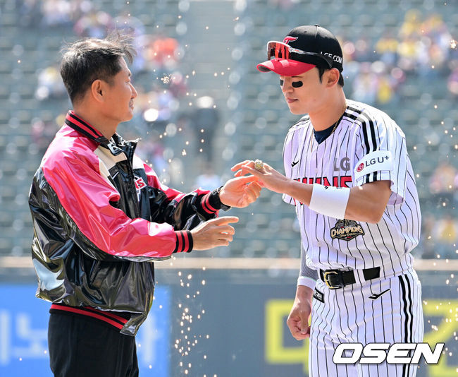 [OSEN=잠실, 지형준 기자] 28일 서울 잠실야구장에서 2026 신한 SOL KBO리그 개막전 LG 트윈스와 KT 위즈의 경기가 열렸다. 이날 LG는 요니 치리노스, KT는 맷 사우어를 선발로 내세웠다.LG 박해민이 김인석 대표이사에게 통합우승 반지를 전달받고 있다. 2026.03.28/ jpnews@osen.co.kr