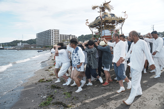 지난해 7월 27일 도쿄 남부 요코스카의 구리하마에서 열린 연례 구리하마 스미요시 신사의 정화 의식에서 ‘미코시(휴대용 신사)’를 바다로 옮기고 있다. 기사 내용의 이해를 돕기 위한 자료사진. AP=연합뉴스