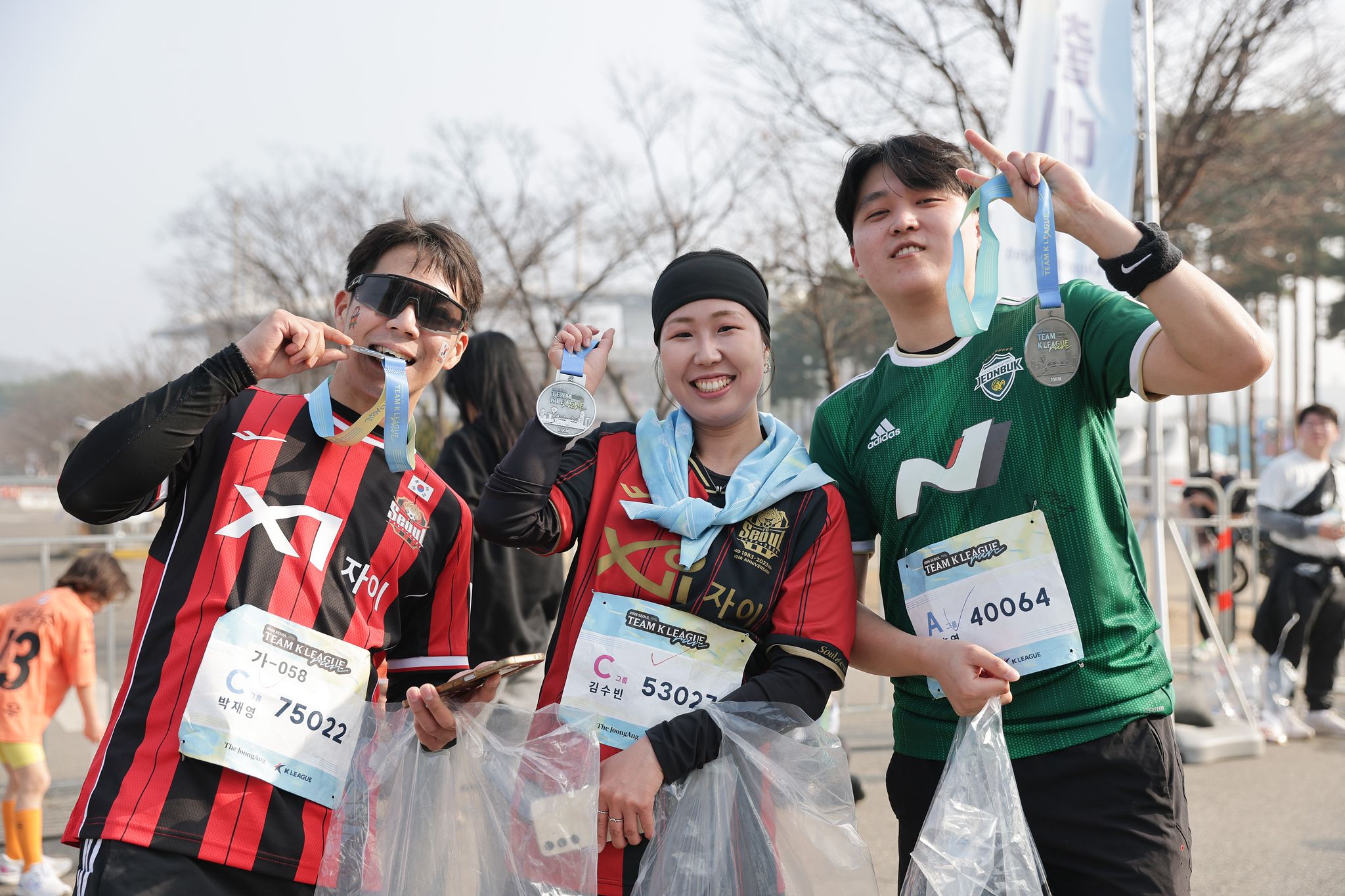 서울 상암동 월드컵공원 평화광장 일대에서 열린 2026 서울 팀 K리그 행사에서 10km를 완주한 뒤 기념 메달을 함께 들어 보이며 포즈를 취한 서울과 전북의 축구 팬. 사진 프로축구연맹