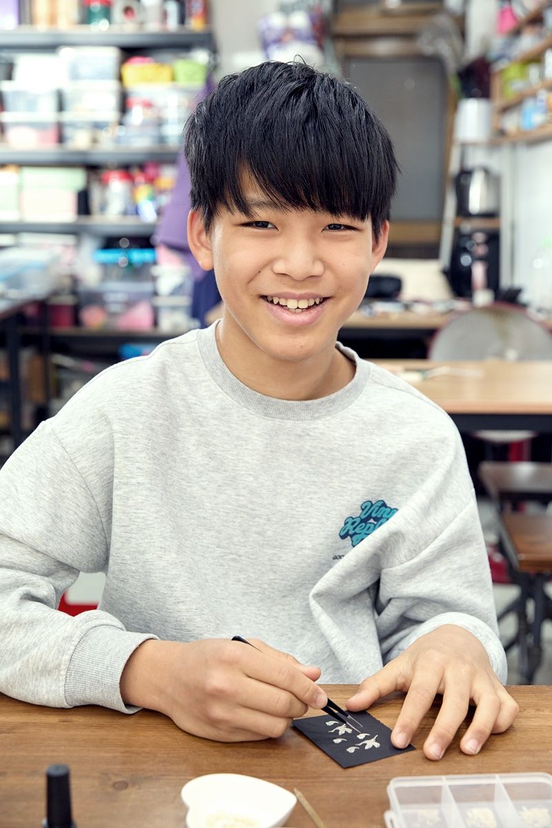 자개로 주체 장식하기 첫 번째 단계인 종이 위에 도안을 그리고 여러 모양의 자개를 조합 중인 정우빈 학생기자. 