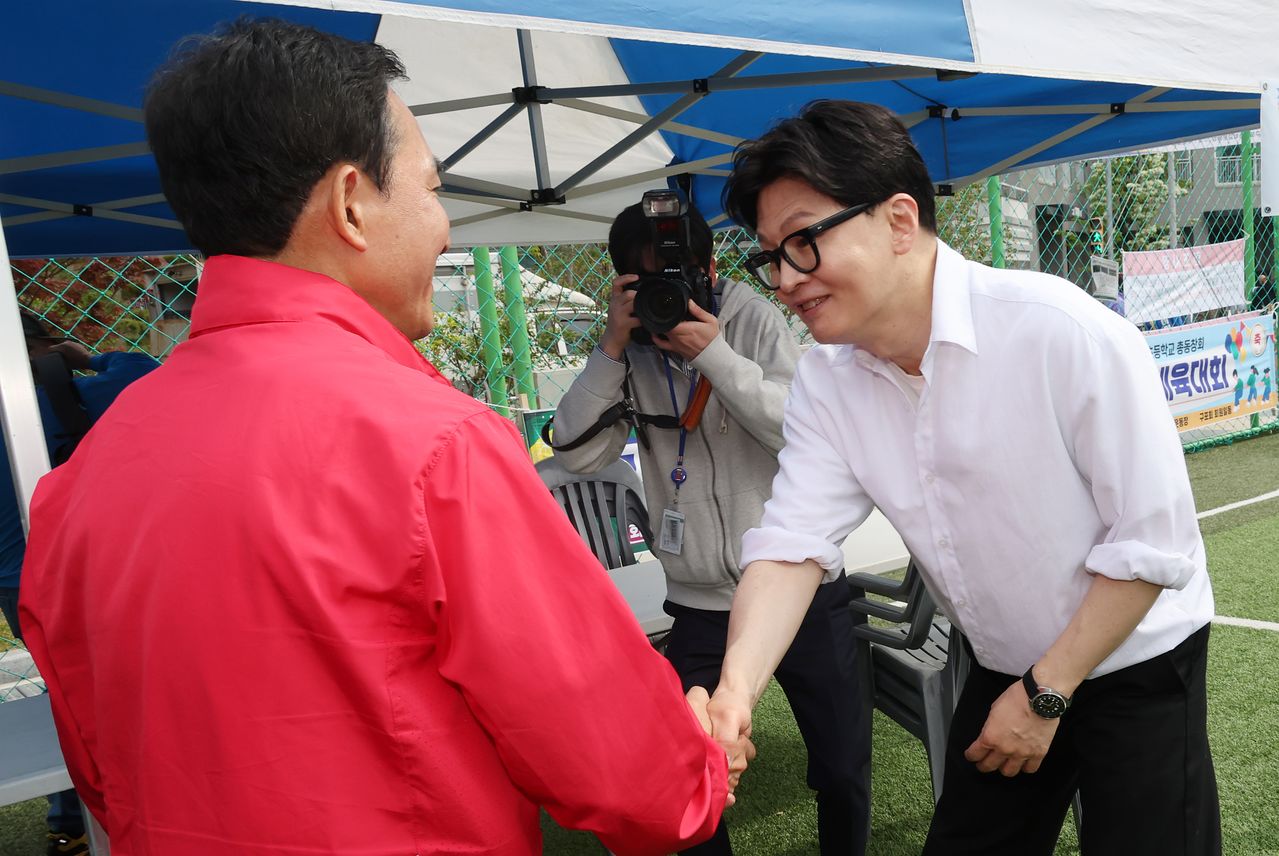 부산 북갑 국회의원 보궐선거에서 국민의힘 예비후보 박민식 전 국가보훈부 장관과 무속소 출마를 공식화한 한동훈 전 국민의힘 대표가 26일 부산 구포초에서 열린 동문 운동회에 참석해 악수하고 있다. 송봉근 객원기자