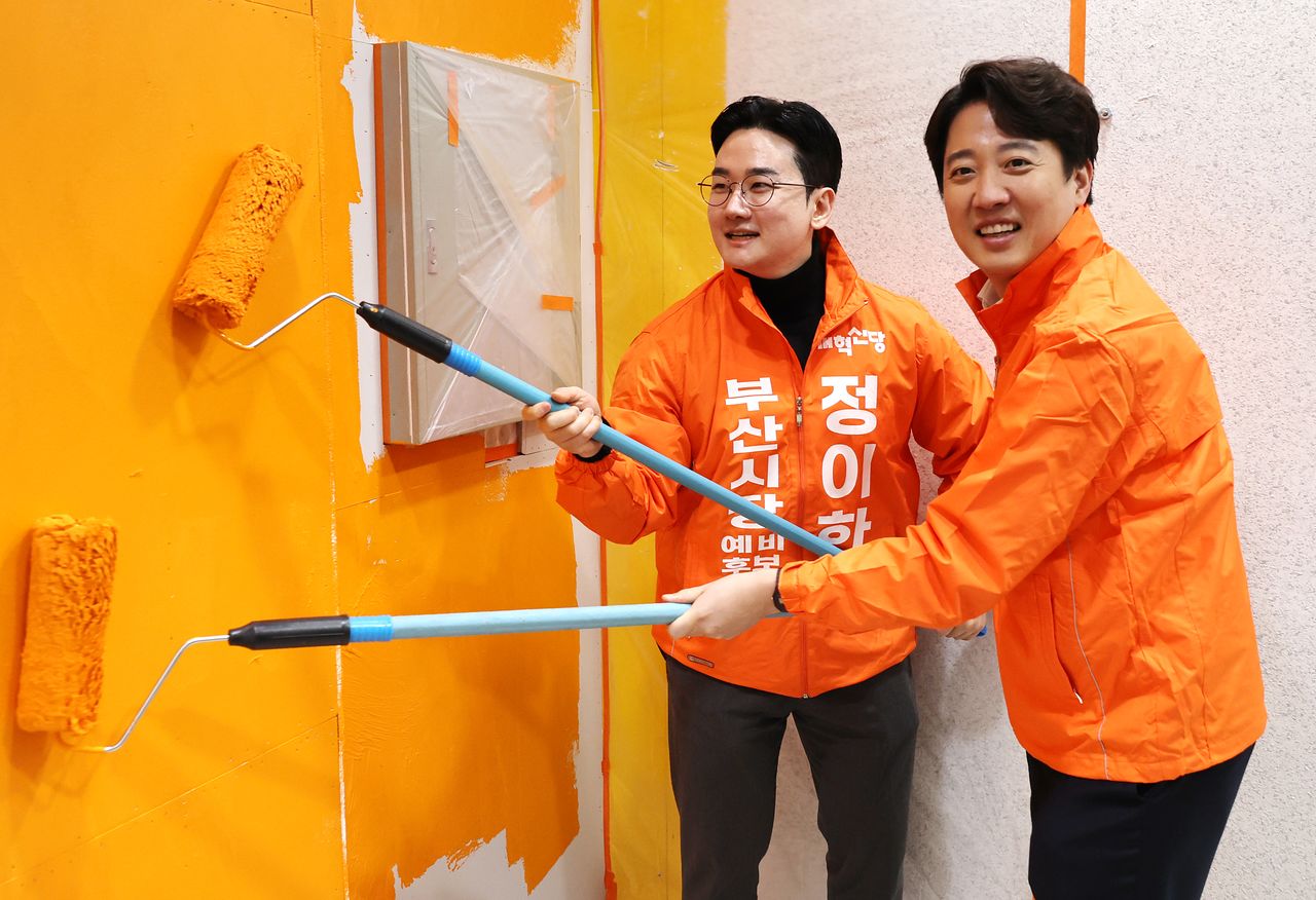 이준석 개혁신당 대표가 지난 2월 27일 부산 부산진구 부전동 정이한 부산시장 예비후보 선거사무소를 찾아 정 예비후보와 함께 당 상징색인 주황색 페인트를 칠하고 있다. 연합뉴스