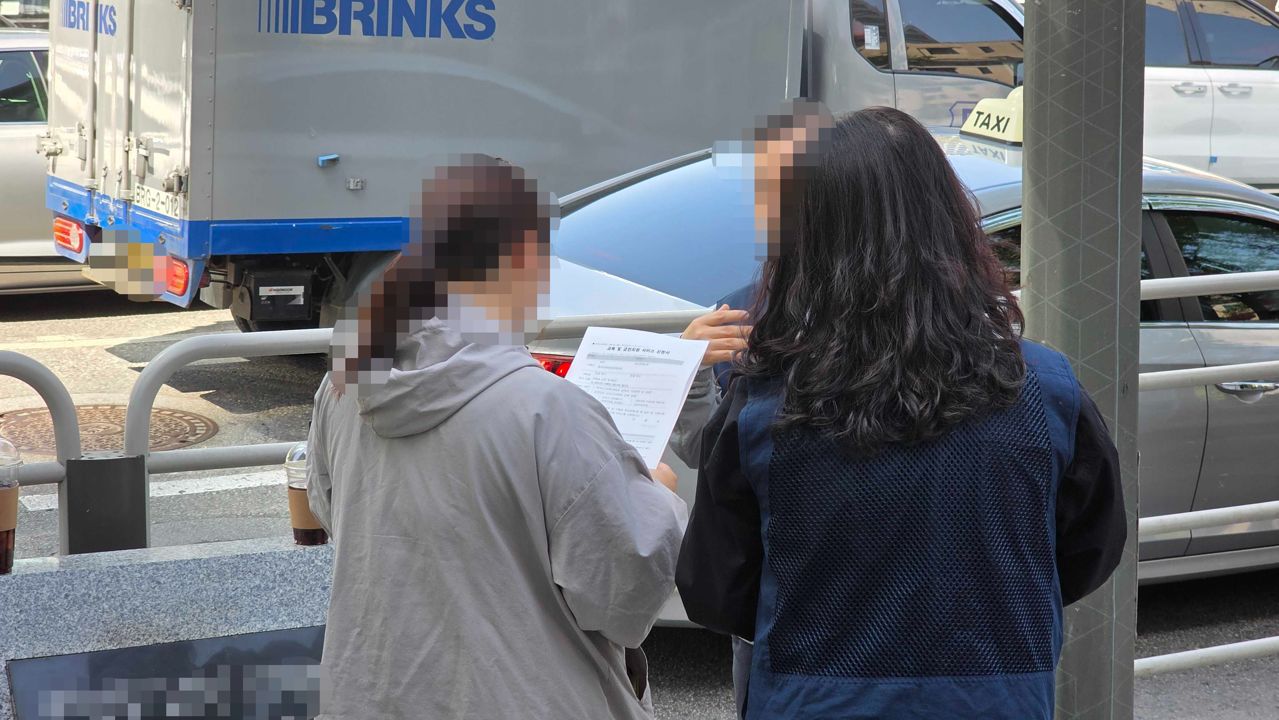 부스 밖에서 흡연해 단속에 걸린 시민이 과태료 고지서를 받아 든 모습. 김창용 기자 