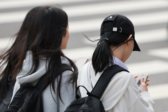 서울의 한 중학교에서 하교하는 학생들. 질병관리청의 2025년 청소년건강행태조사에 따르면 국내 청소년의 주중 스마트폰 사용 시간은 남학생 약 4.2시간, 여학생 약 4.9시간이다. 주말에는 남학생 6시간, 여학생 7시간을 넘긴다. 연합뉴스 