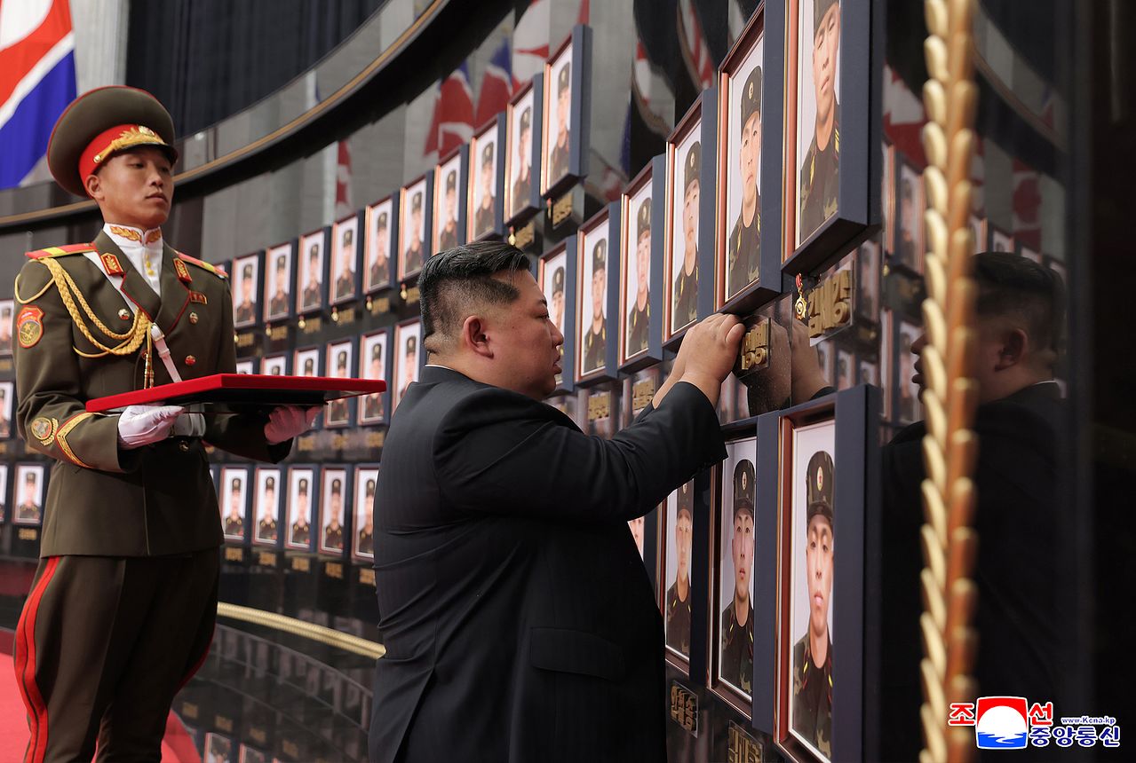 지난해 8월 김정은 국무위원장이 러시아·우크라이나 전쟁 전사자 초상 옆에 공화국 영웅 메달을 달아주고 있다. 조선중앙통신