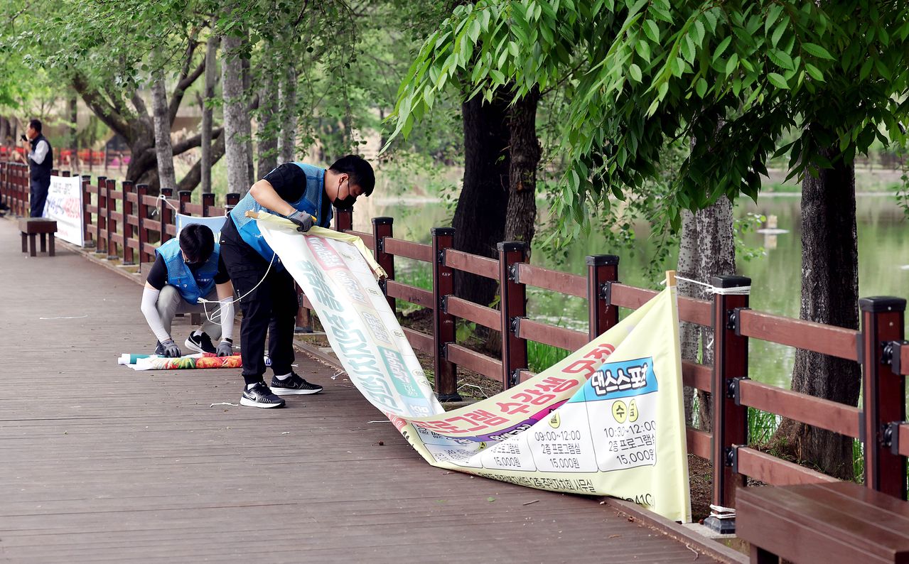 20일 오전 광주 북구 용봉동 용봉제 인근 도로에서 북구청 직원들이 불법 현수막을 떼고 있다.   이날부터 광주시는 5개 자치구에 있는 1곳을 현수막 없는 거리로 지정해 현수막 단속에 나섰다. 기사와 직접적인 관련 없음. 사진 광주 북구