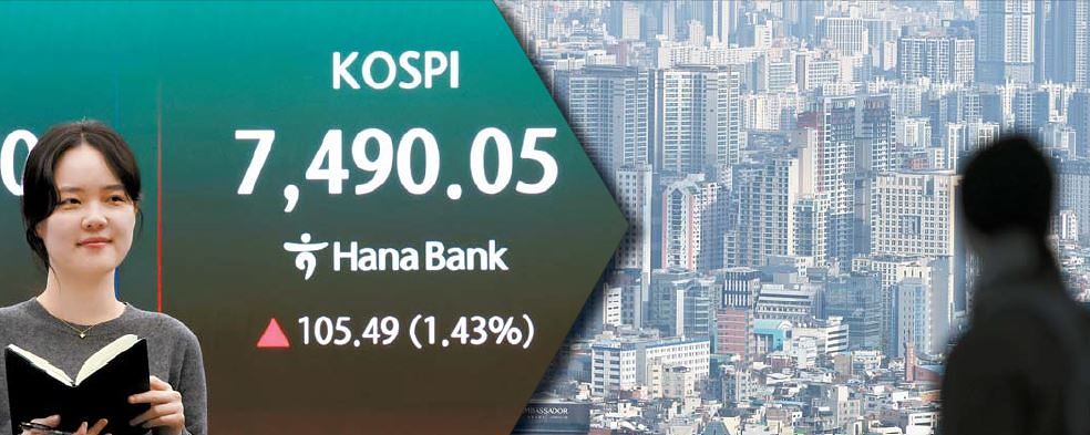 7일 코스피 지수가 전날보다 105.49포인트(1.43%) 상승한 7490.05를 기록하며 사상 최고치를 다시 경신했다. 서울 중구 하나은행 본점 딜링룸 전광판에 이날 종가가 표시되고 있다(왼쪽 사진). 오른쪽은 남산에서 바라본 서울시내 아파트단지 모습. 김종호 기자, [뉴스1]