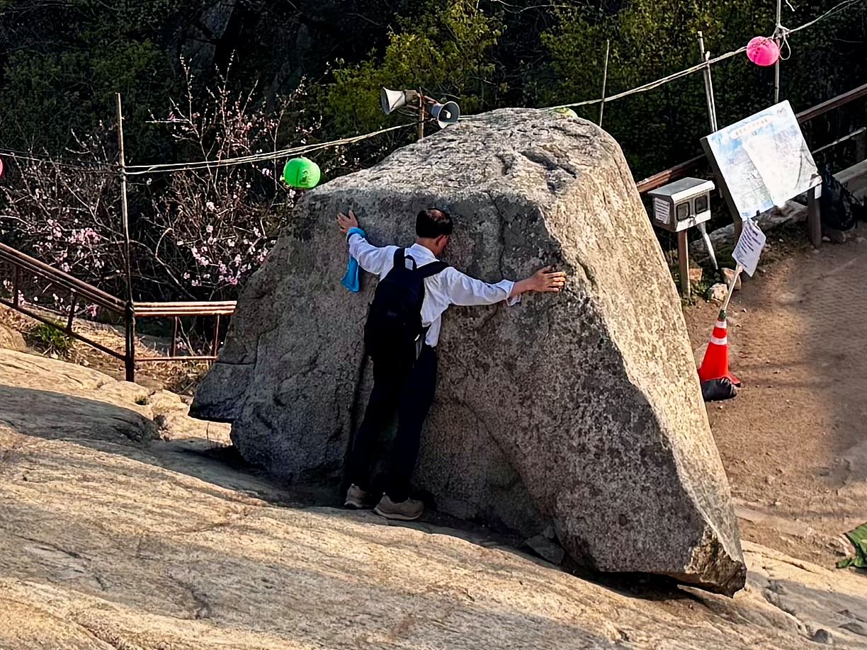 관악산 정상의 너른 바위 차일암에서 한 남성이 기운을 받으려는 듯 정상석을 껴안고 있다. 김홍준 기자 