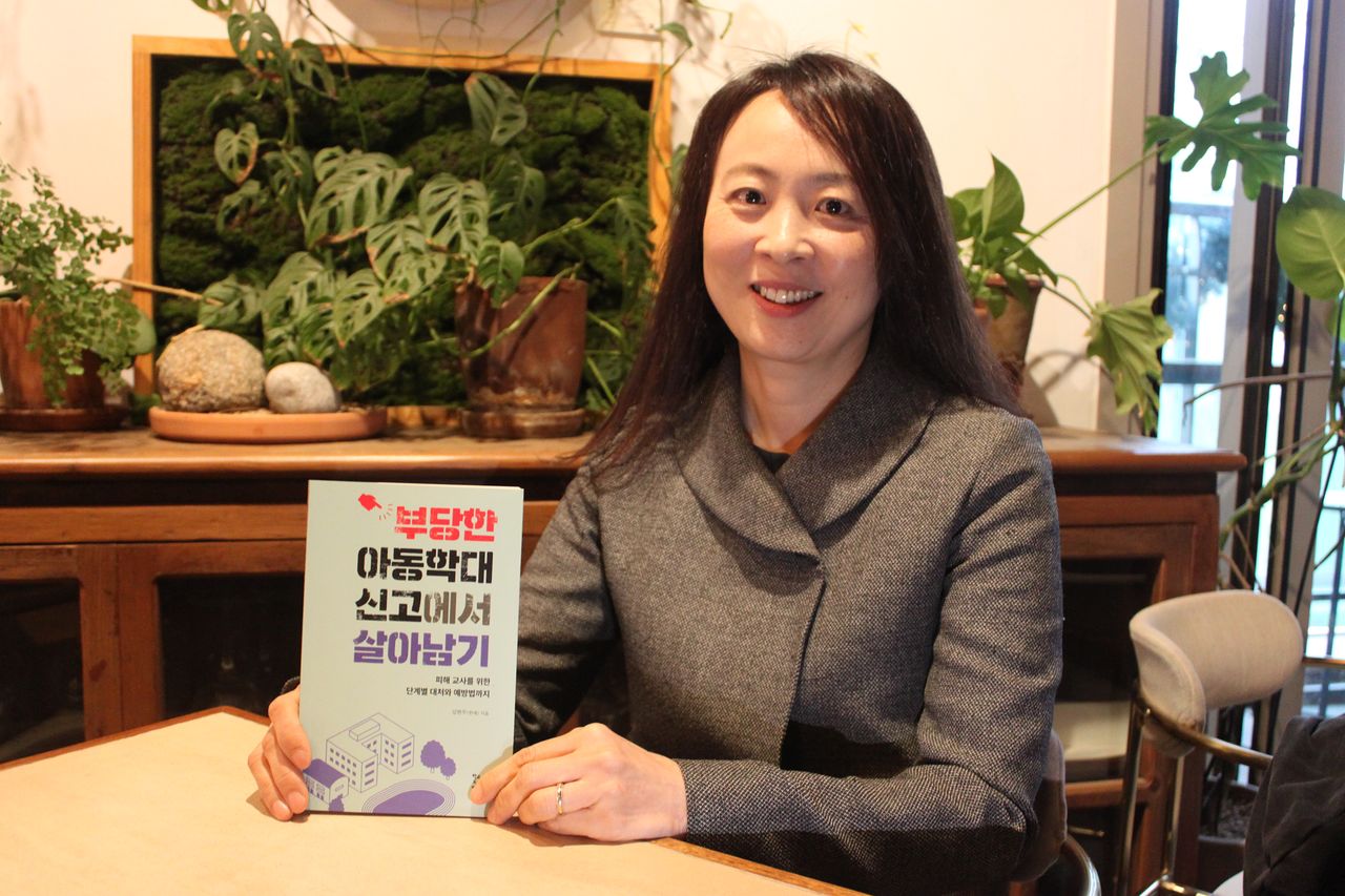 지난달 29일 서울 서초구의 한 카페에서 김현주 교사가 자신이 펴낸 『부당한 아동학대 신고에서 살아남기』를 들어보이고 있다. 김민상 기자