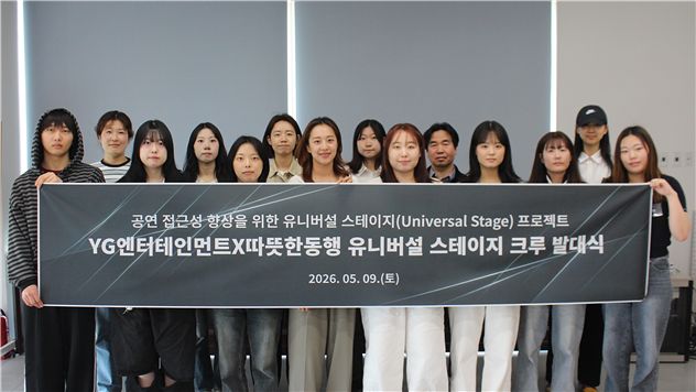 따뜻한동행과 YG엔터테인먼트가 진행한 '유니버설 스테이지 크루' 발대식에서 참여자들이 현수막을 들고 기념촬영을 하고 있다.