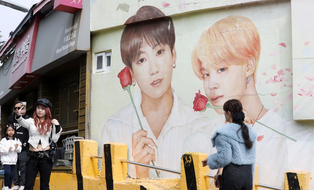 지난 3월 19일 부산 서구 감천문화마을에서 외국인 관광객들이 부산이 고향인 BTS 멤버 정국·지민이 그려진 대형 벽화를 배경으로 기념촬영을 하고 있다. 사진 뉴스1