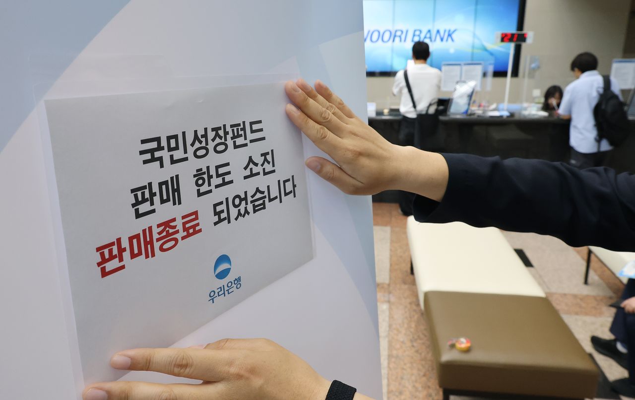 국민참여성장펀드 가입 첫날인 22일 서울 중구 우리은행 본점 영업점에서 한 직원이 한도소진으로 인한 판매종료 안내문을 붙이고 있다. 연합뉴스