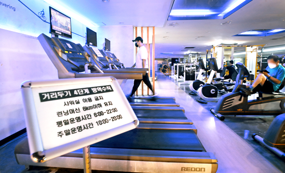 2021년 7월 12일 사회적 거리두기 4단계 첫날 서울 은평구 연신내 한 헬스장 모습. 당시 회원들이 마스크를 낀 채 런닝머신 등 기구를 이용하고 있다. 샤워실을 이용할 수 없고 런닝머신은 시속 6km이하의 속도를 유지해야 한다. 뉴시스