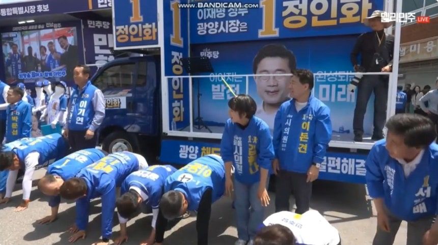 지난 24일 전남 광양시 옥곡 5일장에서 유세 중이던 더불어민주당 후보자들이 엎드려뻗쳐 동작을 하고 있다. 사진 델리민주 캡쳐