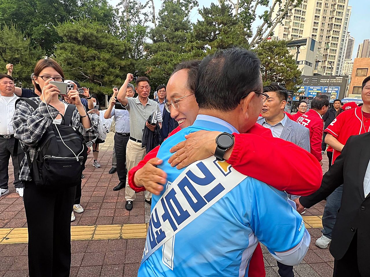 김부겸 더불어민주당 대구시장 후보와 추경호 국민의힘 대구시장 후보가 지난 24일 대구FC 홈구장인 대구IM뱅크파크 앞에서 각자의 유세를 마치고 유세차에서 내려와 포옹하며 격려하고 있다. 독자 제공