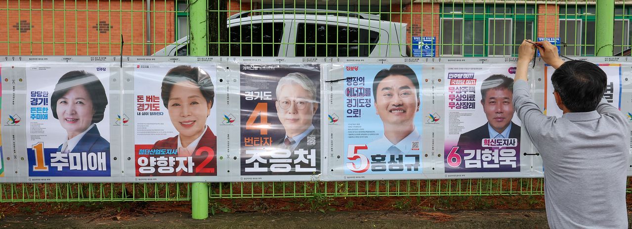 경기도선거관리위원회 직원들이 제9회 전국동시지방선거 공식 선거운동이 시작된 지난 21일 경기 수원시 팔달구 율현중학교 펜스에 경기도지사 후보 선거벽보를 첩부하고 있다. 뉴스1
