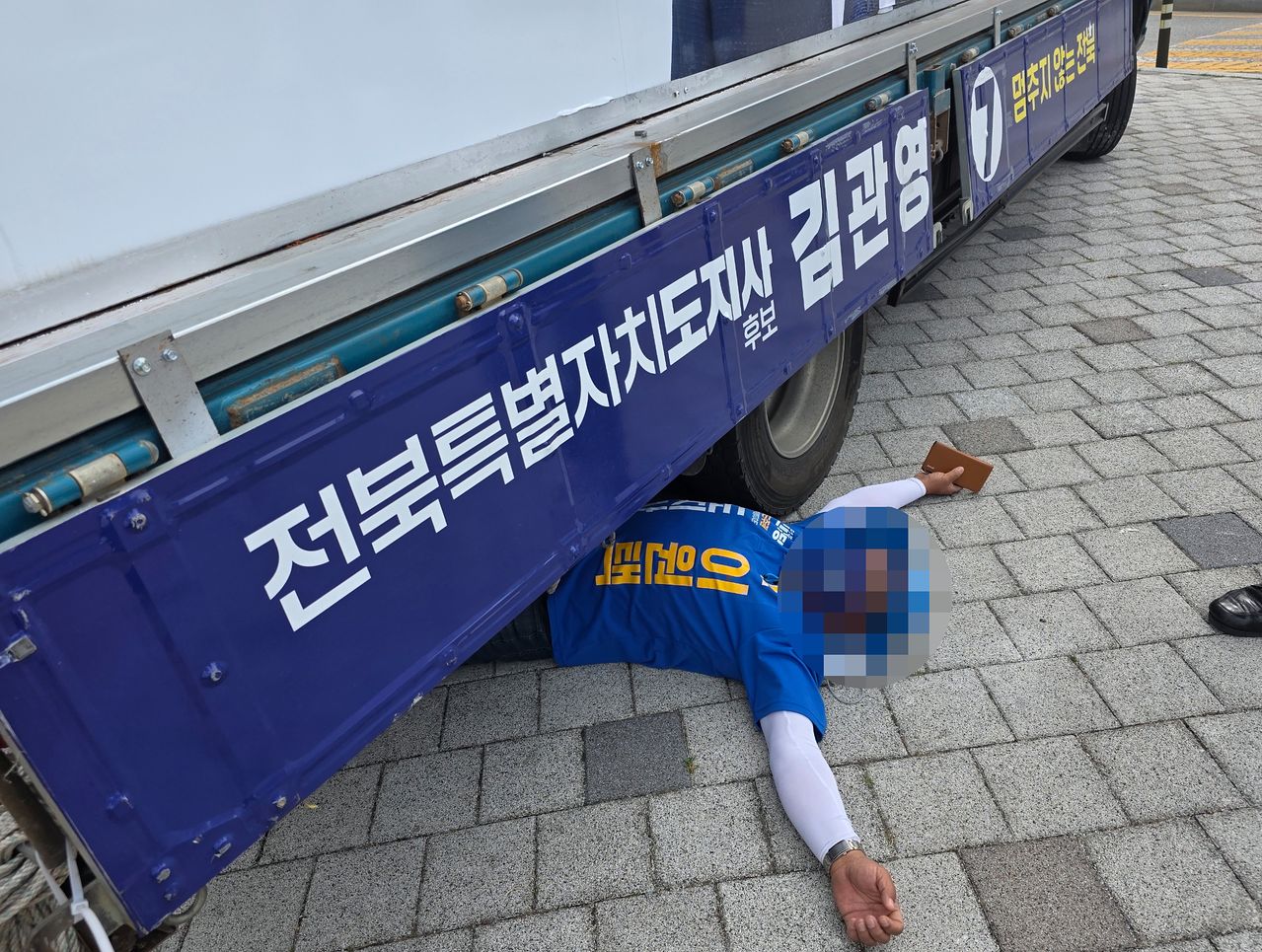 1일 오전 8시30분쯤 전북 전주시 완산구 효자동의 한 사거리에서 이원택 더불어민주당 전북도지사 후보의 선거운동원이 김관영 무소속 후보 유세차 밑으로 들어가 드러누워 있다. 연합뉴스