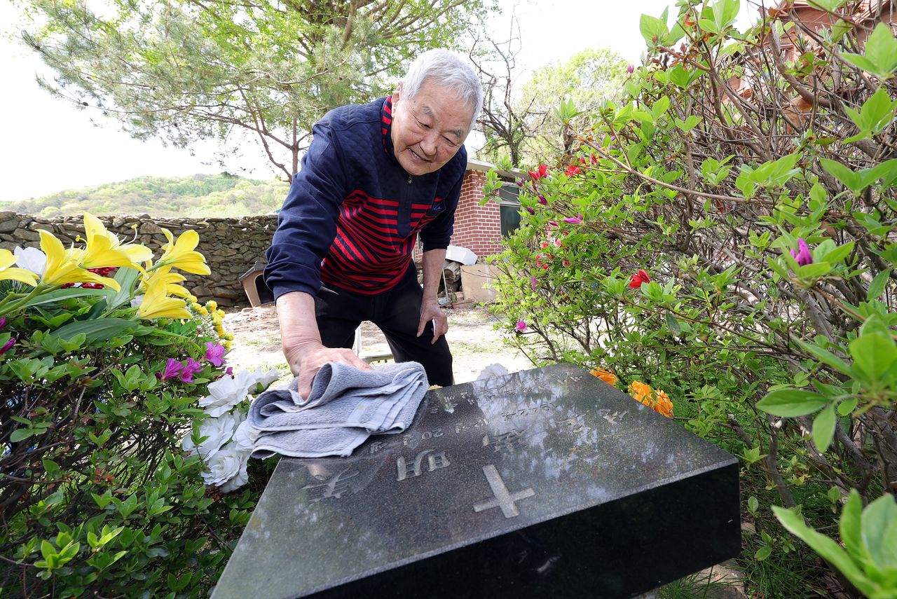신영교 작곡가가 22년 전 세상을 떠난 아내의 묘비를 닦고 있다. 그는 아내를 자택 앞마당에 묻었다. 강정현 기자