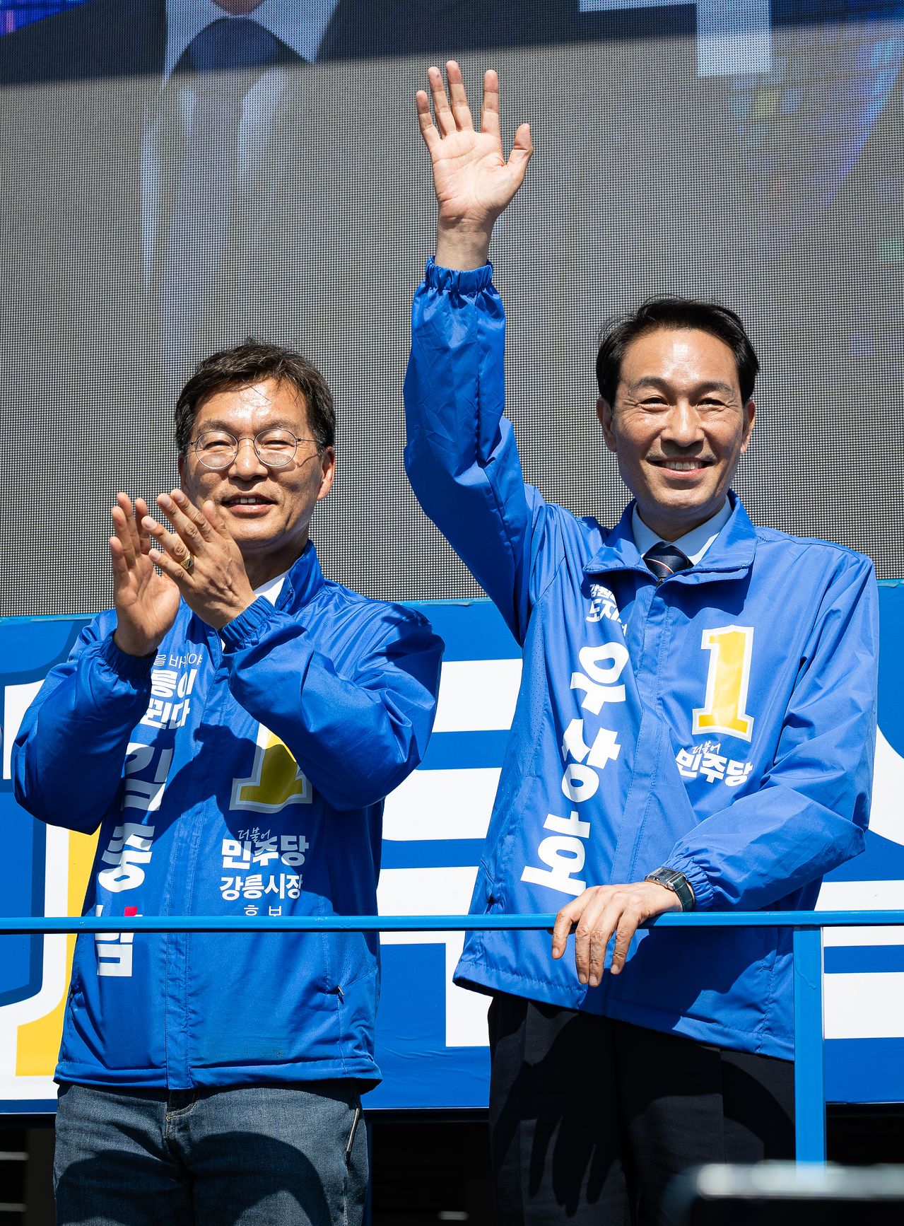 더불어민주당 우상호 강원특별자치도지사 후보, 김중남 강릉시장 후보가 지난달 22일 강원 강릉시 주문진 시장 앞에서 시민들을 향해 인사하고 있다. [뉴스1]