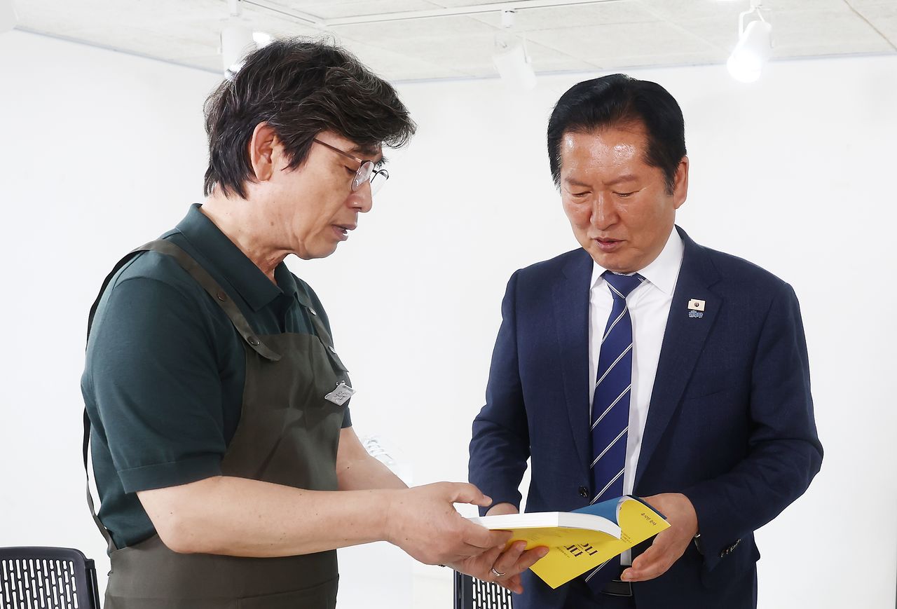 정청래 더불어민주당 대표가 지난 4월 24일 오후 서울 성동구 언더스탠드에비뉴에 마련된 청각장애인 수제화 브랜드 '아지오' 매장 오픈 행사에 참석, 유시민 작가로부터 사랑이 있으니 살아집디다 책을 전달 받고 있다. 뉴스1