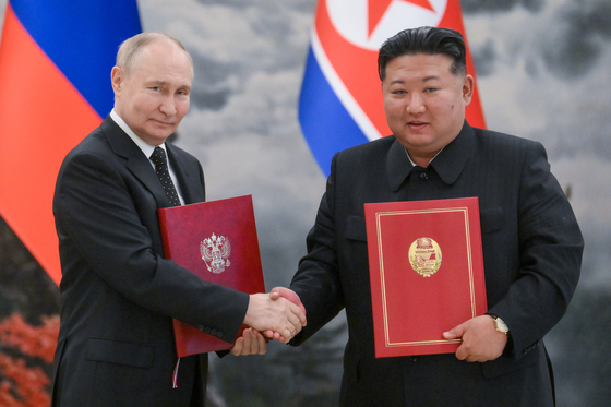 블라디미르 푸틴 러시아 대통령(왼쪽)과 김정은 북한 국무위원장이 2024년 6월 19일 평양에서 정상회담 뒤 서명한 조약을 들어 보이고 있다. 타스, 연합뉴스