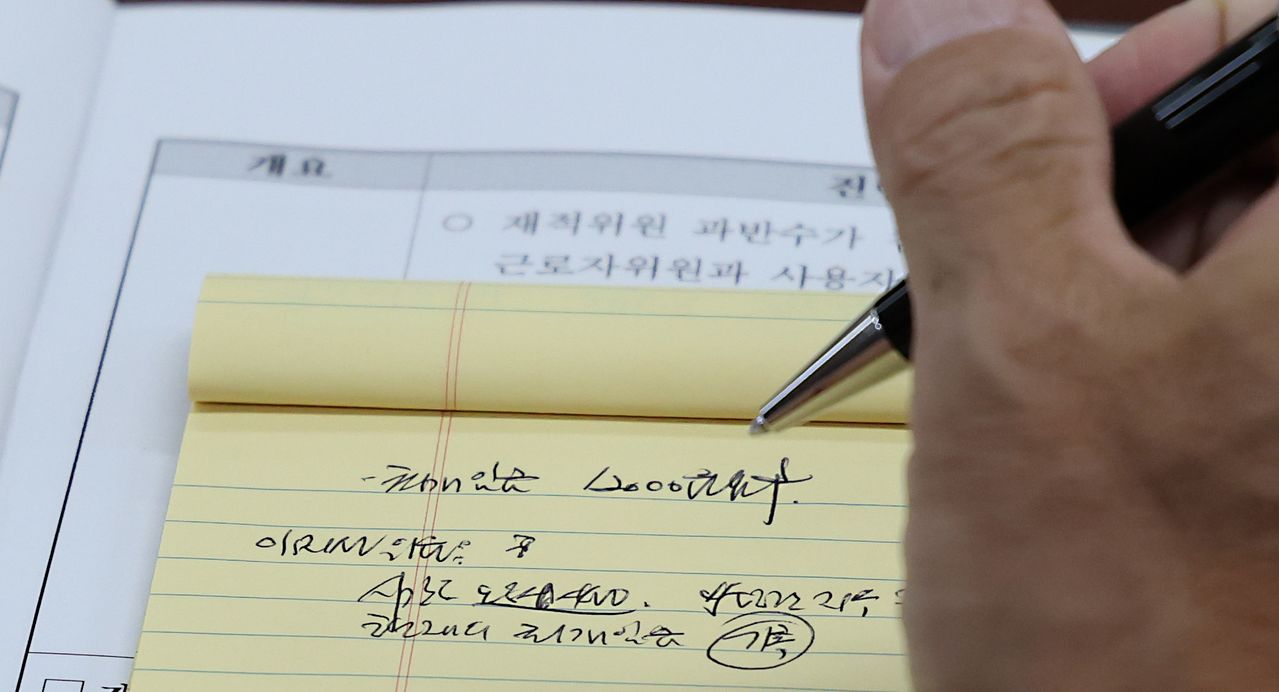 권순원 최저임금위원장이 23일 세종시 정부세종청사 최저임금위원회에서 열린 8차 전원회의에서 근로자위원의 2027년 최저임금 1만2000원 요구 발언을 메모하고 있다. 뉴스1