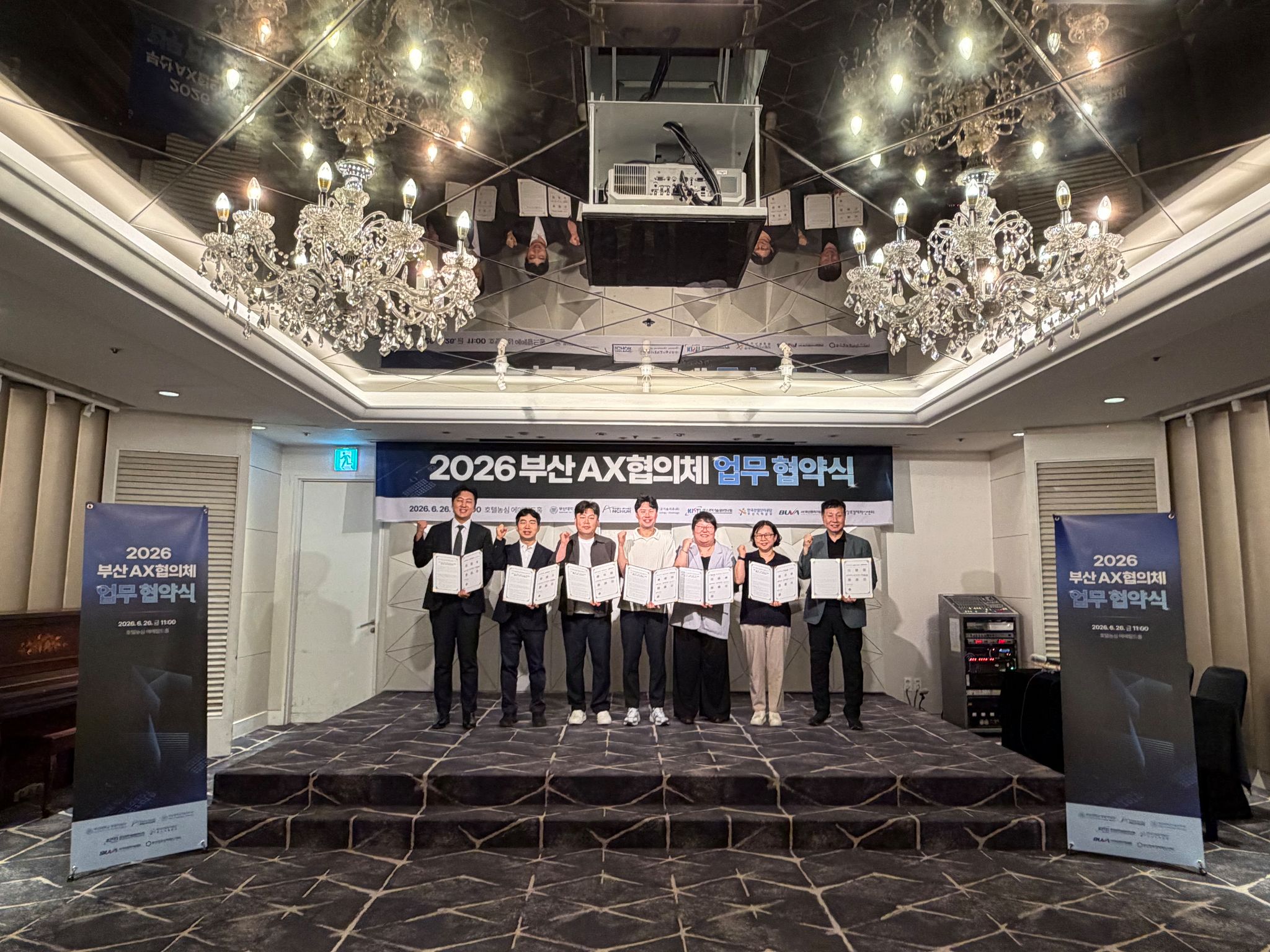 최재경 한국과학기술정보연구원 부산울산경남지원 박사, 김원섭 한국산업단지공단 부산지역본부 팀장, 박태옥 부산벤처기업협회 사무국장, 김남용 부산대학교 기술지주 팀장, 조은혜 부산대학교 앵커사업단 부장, 김민영 부산대학교 창업지원단 부장, 최군오 (재)부산창조경제혁신센터 실장(왼쪽부터)이 6월 26일 열린 부산 AX 협의체 업무협약식에서 기념촬영을 하고 있다.