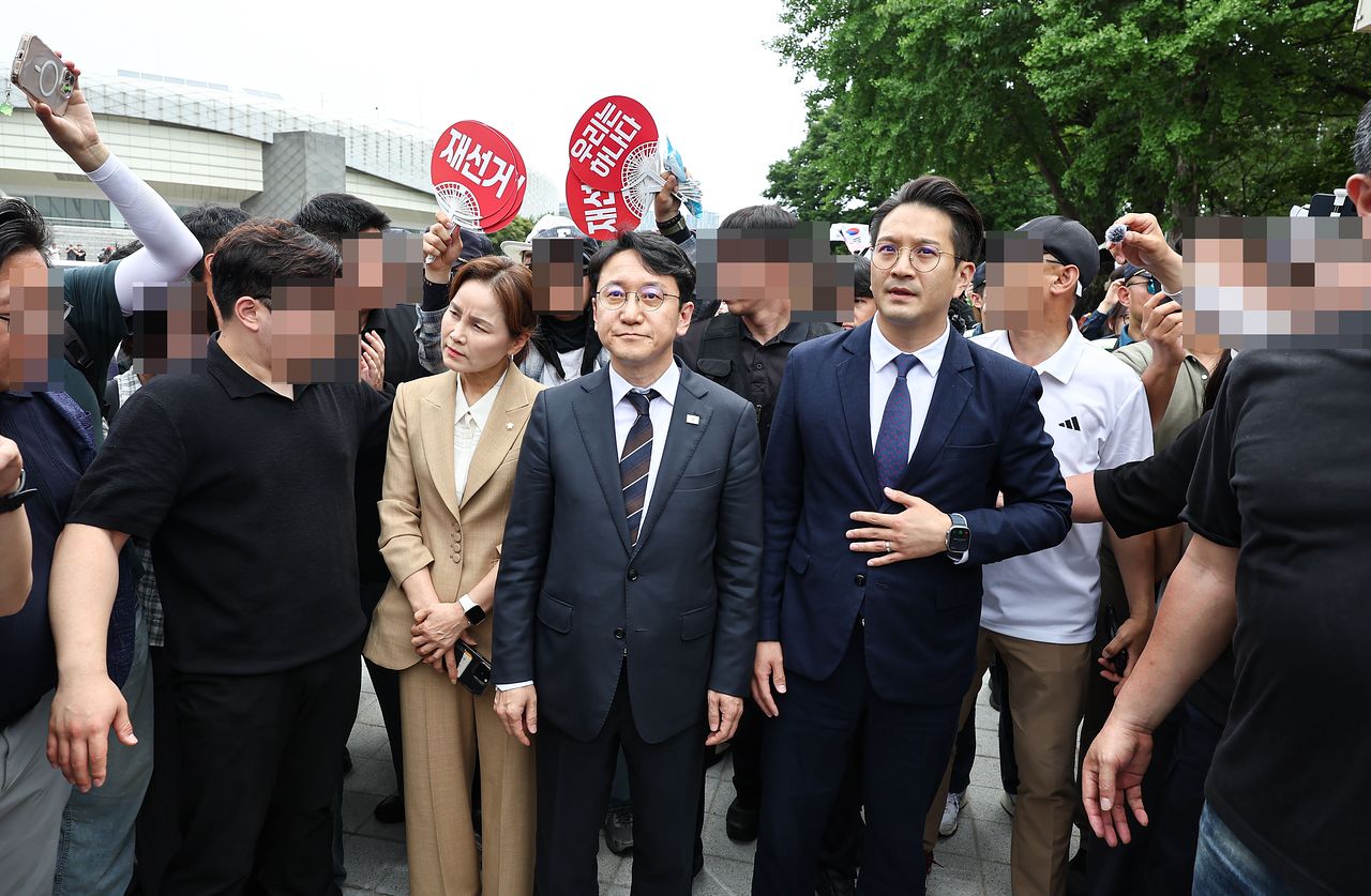 임오경, 천준호, 전용기 더불어민주당 의원이 17일 서울 송파구 올림픽공원 핸드볼경기장 앞에서 투표용지 부족 사태를 규탄하는 시민들에게 항의를 받으며 이동하고 있다. 뉴스1