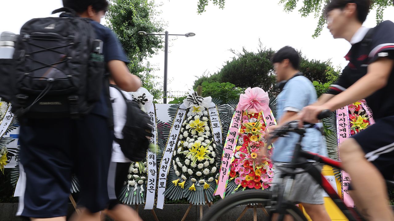 지난 2일 서울 강동구 배재고 앞에 야구부를 비판하는 근조화환과 응원하는 화환이 놓여 있는 가운데 학생과 시민들이 지나가고 있다. 해당 화환은 구청과 협의해 2일 오후 철거됐다. 뉴스1